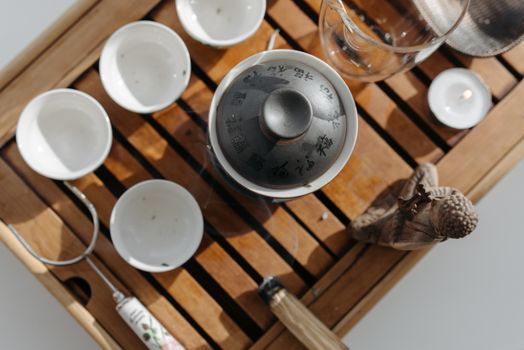 Traditional tea ceremony set on a wooden tray with teapot and cups captured from above.