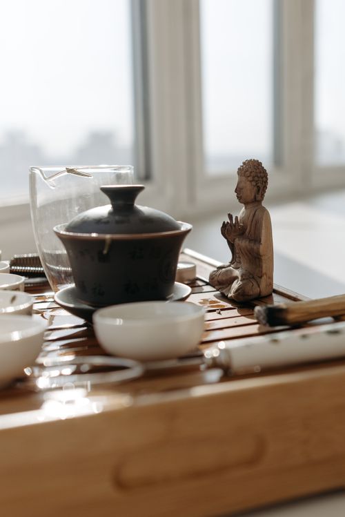 Free Tranquil setting showcasing a Buddha figurine and tea setup on a wooden surface. Stock Photo