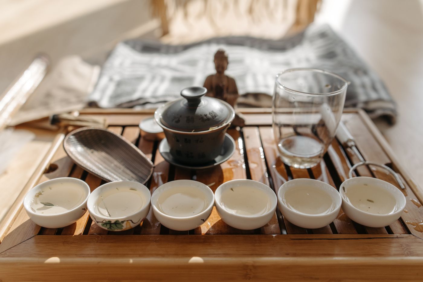 Small gongfu tea cups and a ceramic tea set on a wooden tray