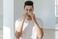 Sick Man in White Shirt Wiping His Nose with Tissue
