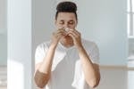 Sick Man in White Shirt Wiping His Nose with Tissue