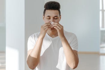 Sick Man in White Shirt Wiping His Nose with Tissue