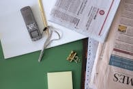 Newspaper Gold Clip and a Notepad on a Green Surface