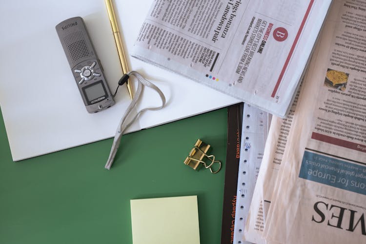 Newspaper Gold Clip And A Notepad On A Green Surface