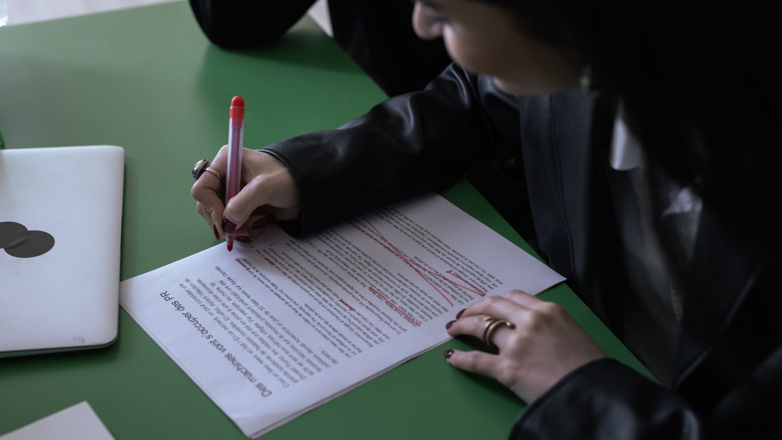 A person marking up a printed document with a red pen