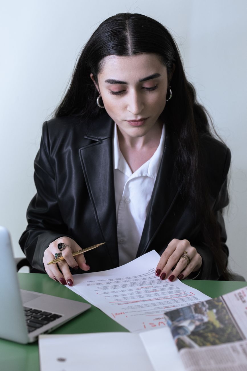 Editor reviewing a laptop draft and paper notes during a document check
