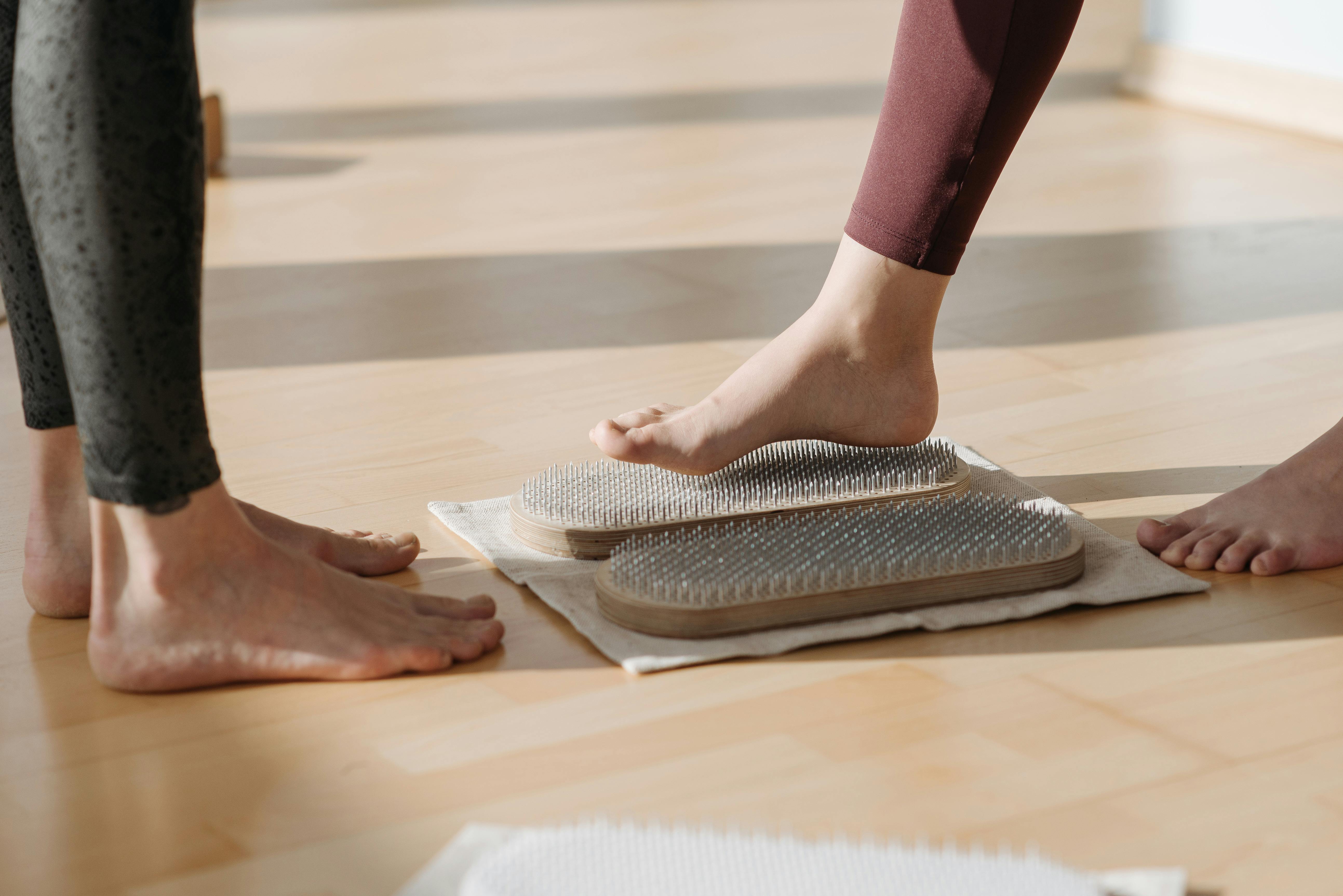 Close-up of people practicing meditation on wooden Sadhu boards indoors.