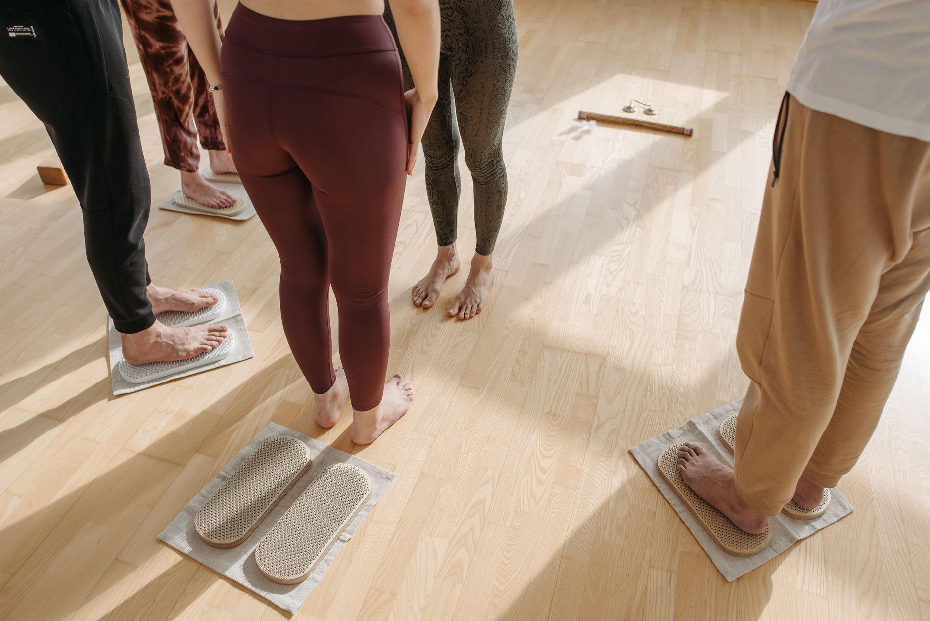 Adults practicing wellness rituals on wooden sadhu boards in an indoor setting.