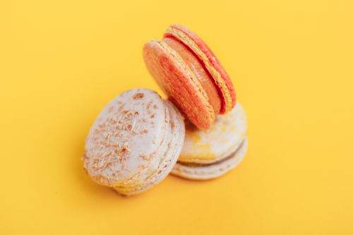 Free From above of delicious little homemade macaroons placed on bright yellow background of studio Stock Photo