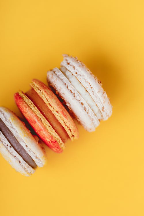 Free Top view of delicious sweet macaroons with delicate cream placed on bright yellow background of studio Stock Photo