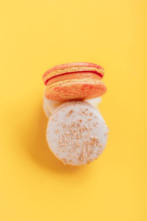 Free Top view of delicious sweet macaroons with gentle cream placed in stack on bright yellow background of studio Stock Photo