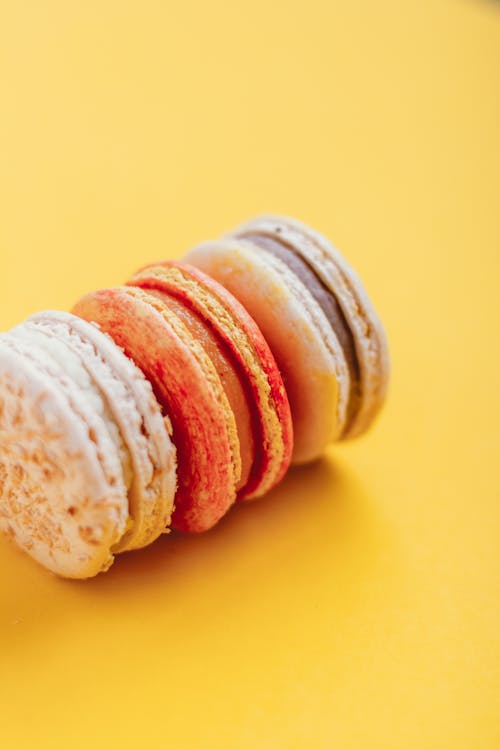 Free From above of tasty colorful macaroons with sweet cream placed on yellow table in daytime Stock Photo