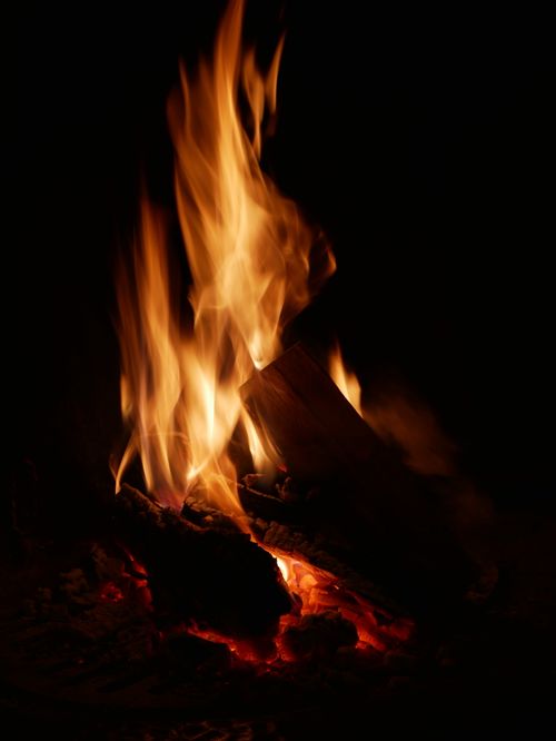 Free Vertical shot of a blazing fire with flames against a dark backdrop, capturing warmth and energy. Stock Photo