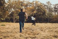 Unrecognizable couple running on meadow in park