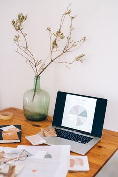 A modern workspace featuring a laptop with a graph, surrounded by documents and a decorative plant, ideal for creative professionals.