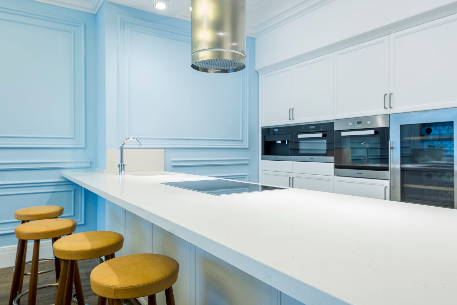 Elegant modern kitchen with minimalist design featuring high stools and sleek white cabinets.