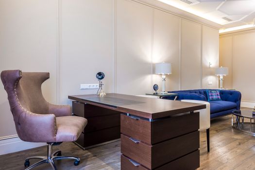 Sleek office interior with a modern desk, plush chair, and stylish decor in neutral tones.