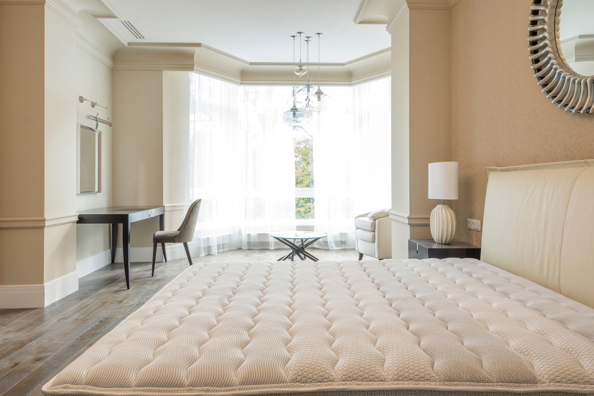 Luxury contemporary bedroom with upholstered bed, side table, lighting and neutral furniture