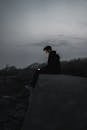 Man Sitting on a Concrete Edge Holding a Pone