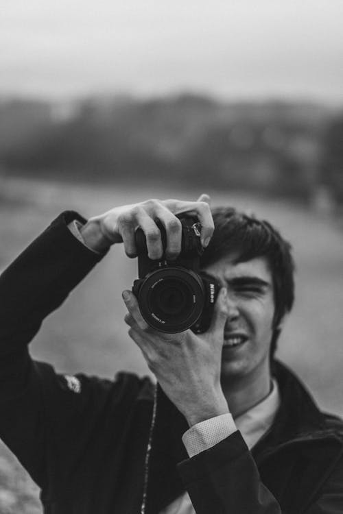 Monochrome Photo of a Man Using a Dslr Camera