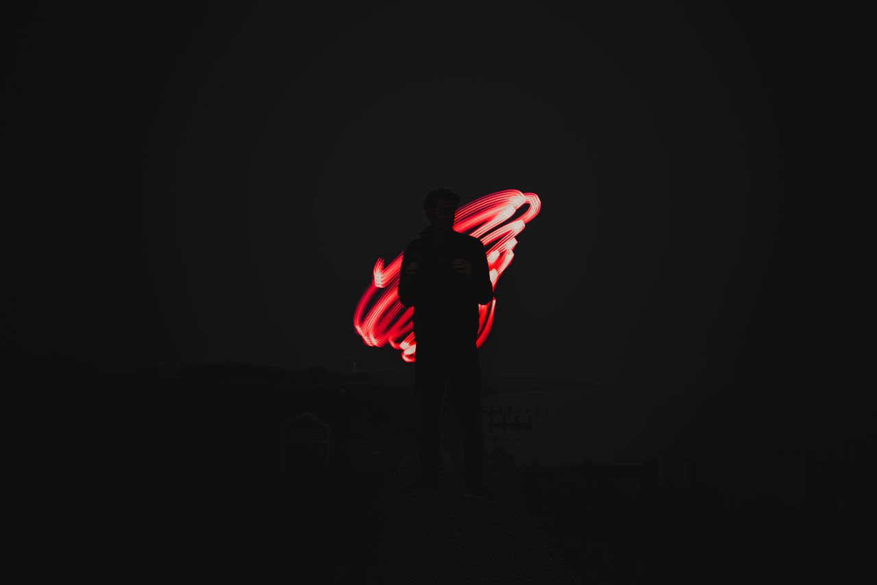 a dramatic silhouette against vibrant red light trails captured in a l