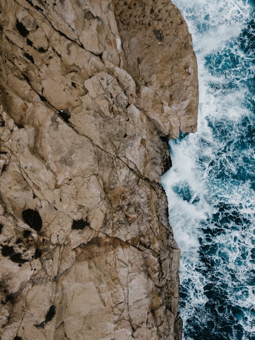 A Top View of Waves Crashing on a Rocky Coast