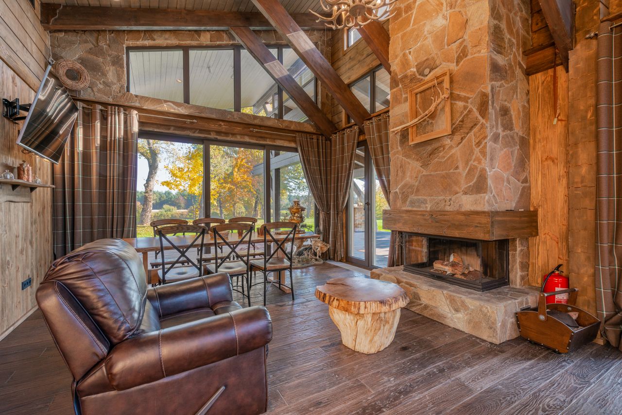 Rustic living room with a brown leather armchair, exposed wood beams, and a stone fireplace