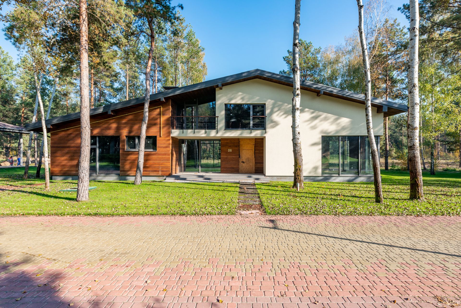 Contemporary house facade set amidst lush greenery and trees.