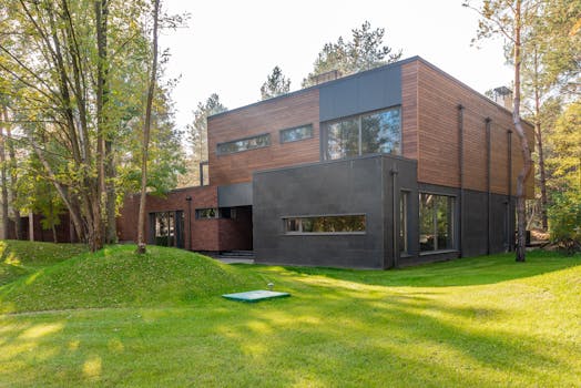 A contemporary wooden house with large glass windows set in a lush forest.