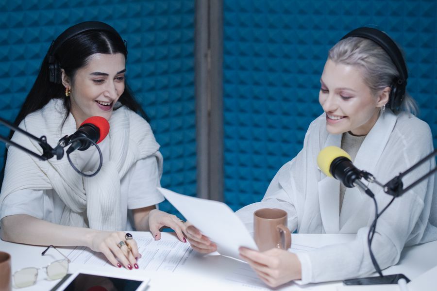 Two podcast hosts leaning into their microphones