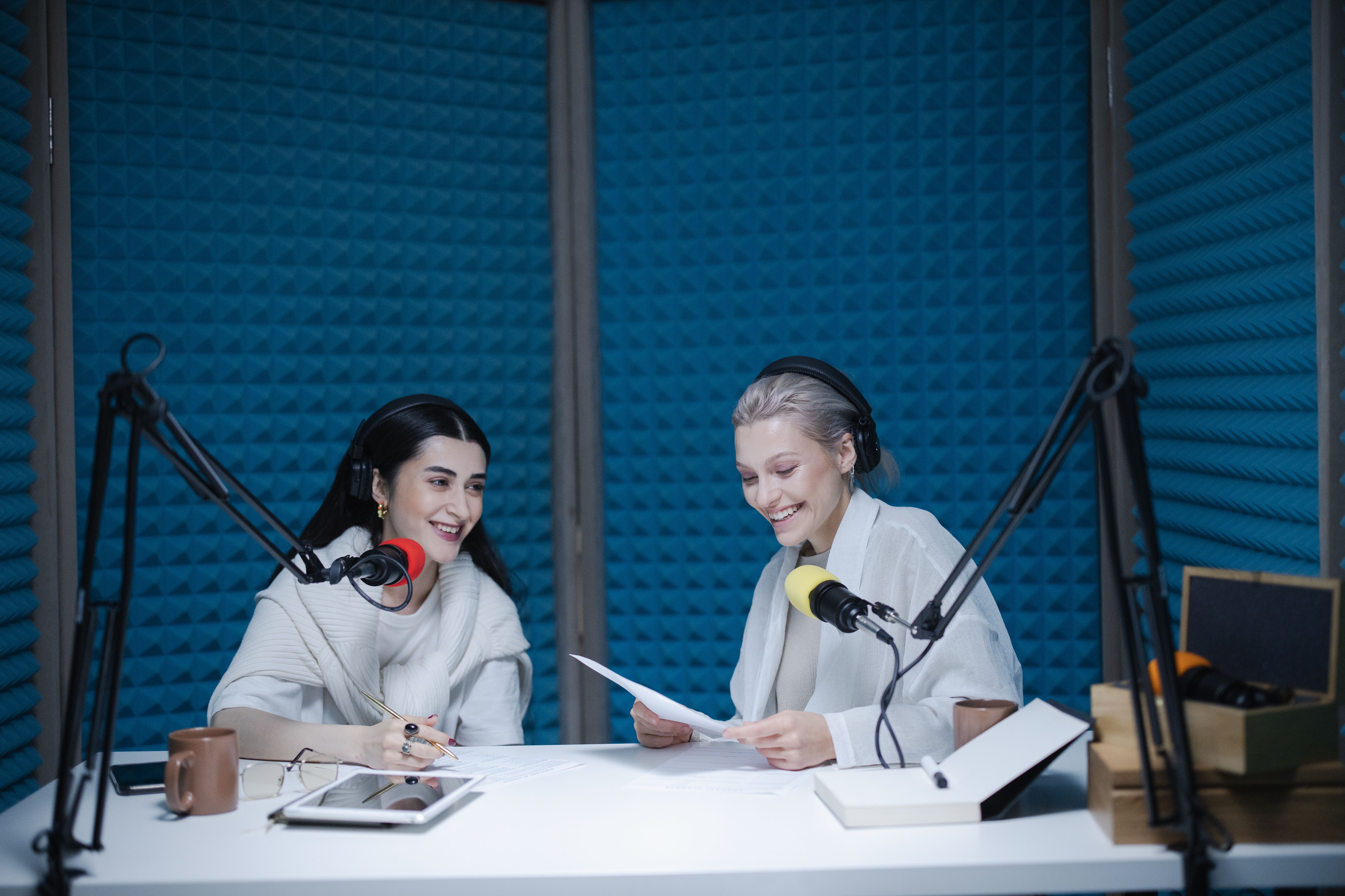 Two people sitting on a table and speaking in microphones