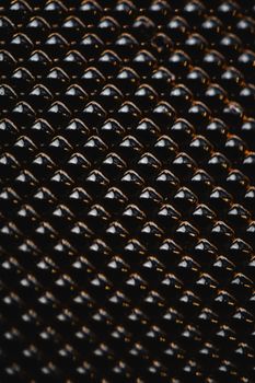 Close-up of abstract black beaded texture with shiny golden highlights creating a geometric pattern.