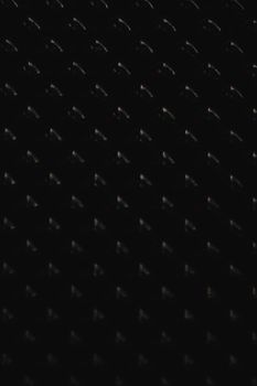 Close-up of a dark abstract pattern with a repetitive design on a black background.