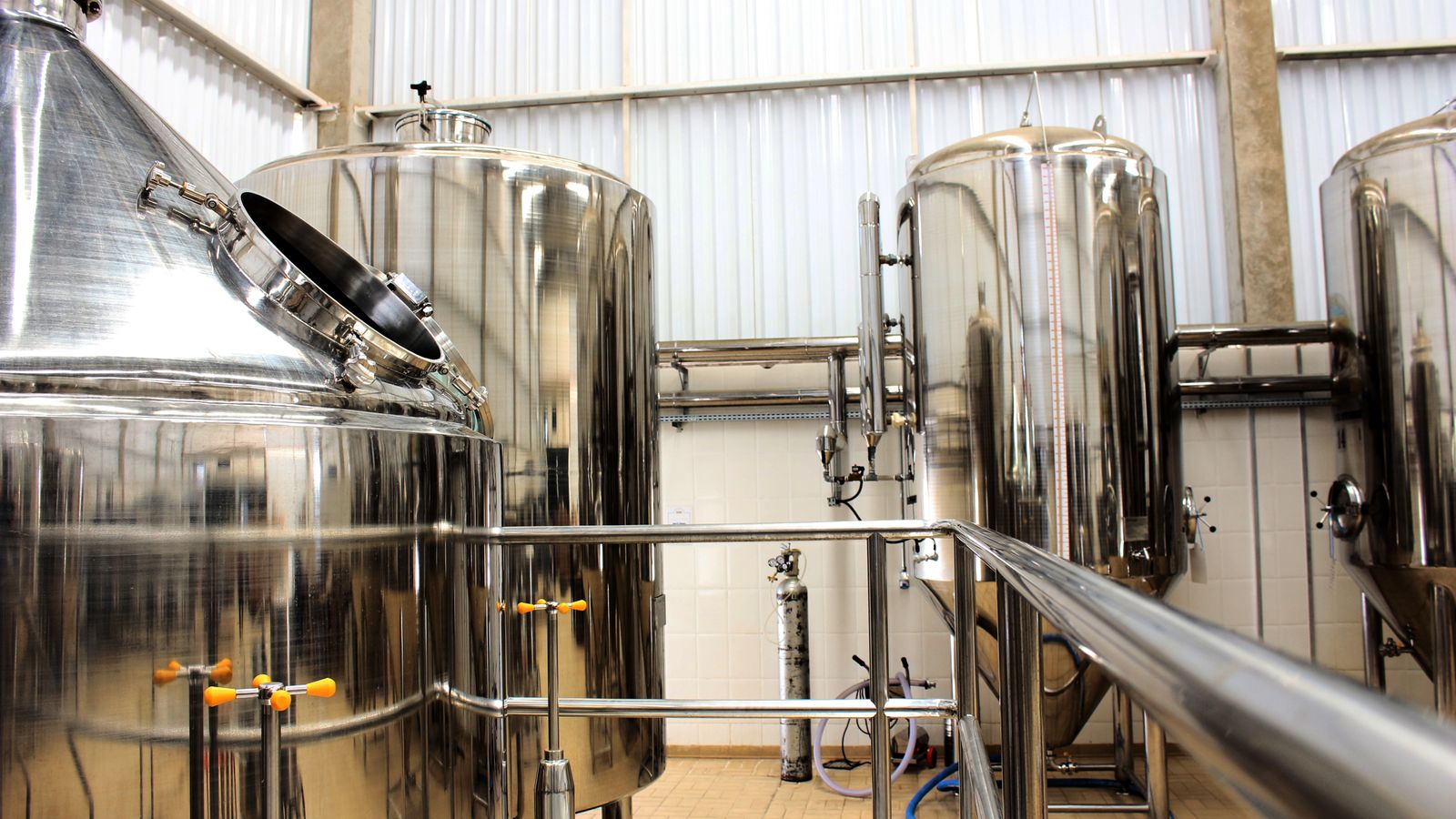 Stainless steel process tanks and piping inside a modern industrial brewery