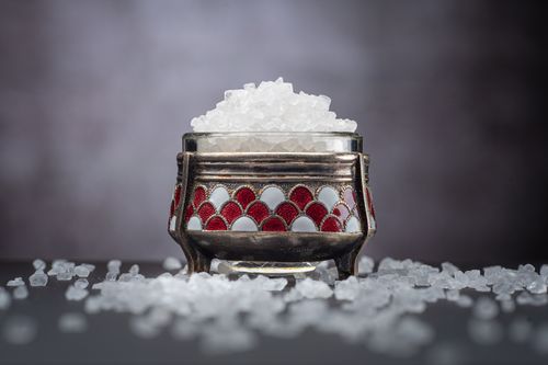 Free Close-up of crystal sea salt in a decorative jar with scattered salt on a dark background. Stock Photo