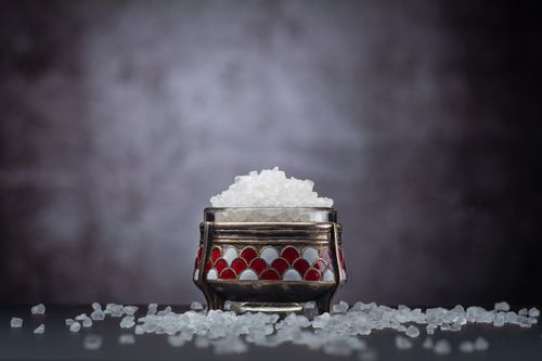 Free Close-up of salt in a beautifully decorated metal container against a blurred background. Stock Photo
