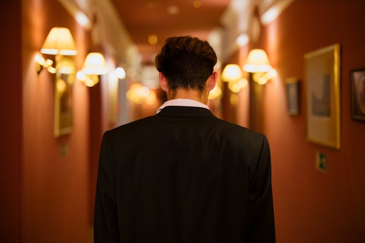 Man In Black Suit Standing In The Hallway