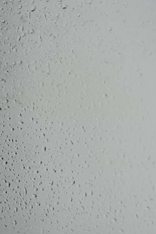 Free Close-up of raindrops on a glass surface creating a textured abstract pattern. Stock Photo