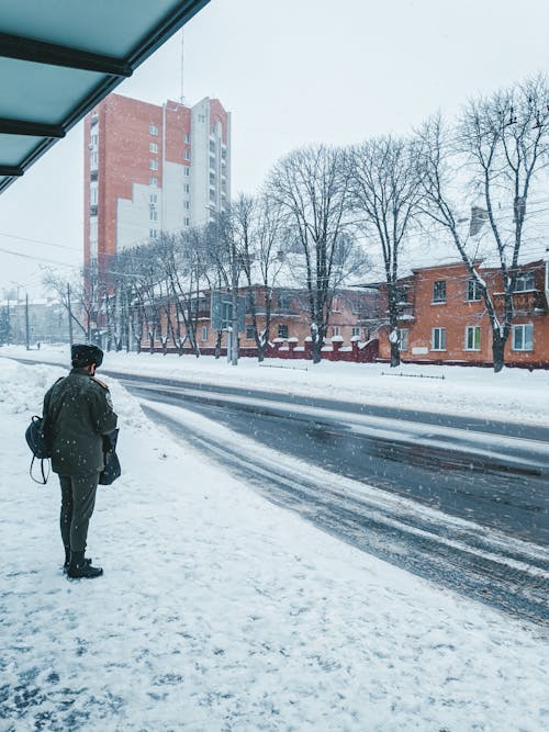 Man Standing on City Street on Snowy Day