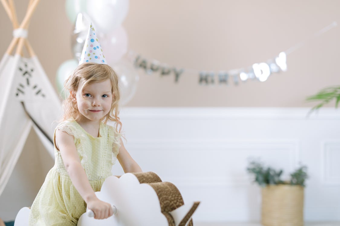 Free Pretty Girl Wearing a Party Hat on a Rocking Horse Stock Photo