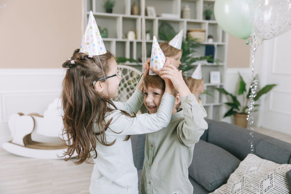Two friends in party hats laughing together with party blowers
