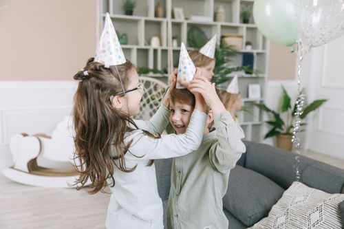 Free Happy kids in party hats enjoying a fun birthday celebration inside a cozy home. Stock Photo