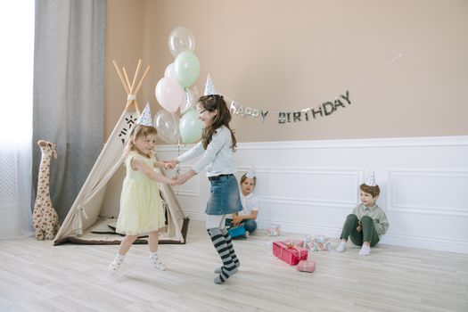 Children having fun at a birthday party with a tent and decorations indoors.