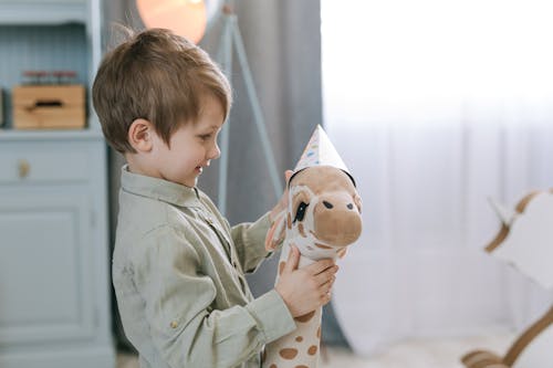 Free A Boy Putting a Party Hat on a Stuffed Animal Stock Photo