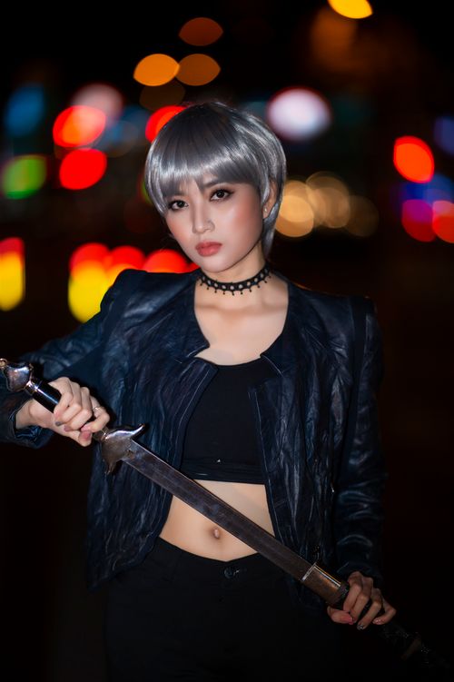 Free Woman with a sword posing confidently against a vibrant, bokeh-filled night background. Stock Photo