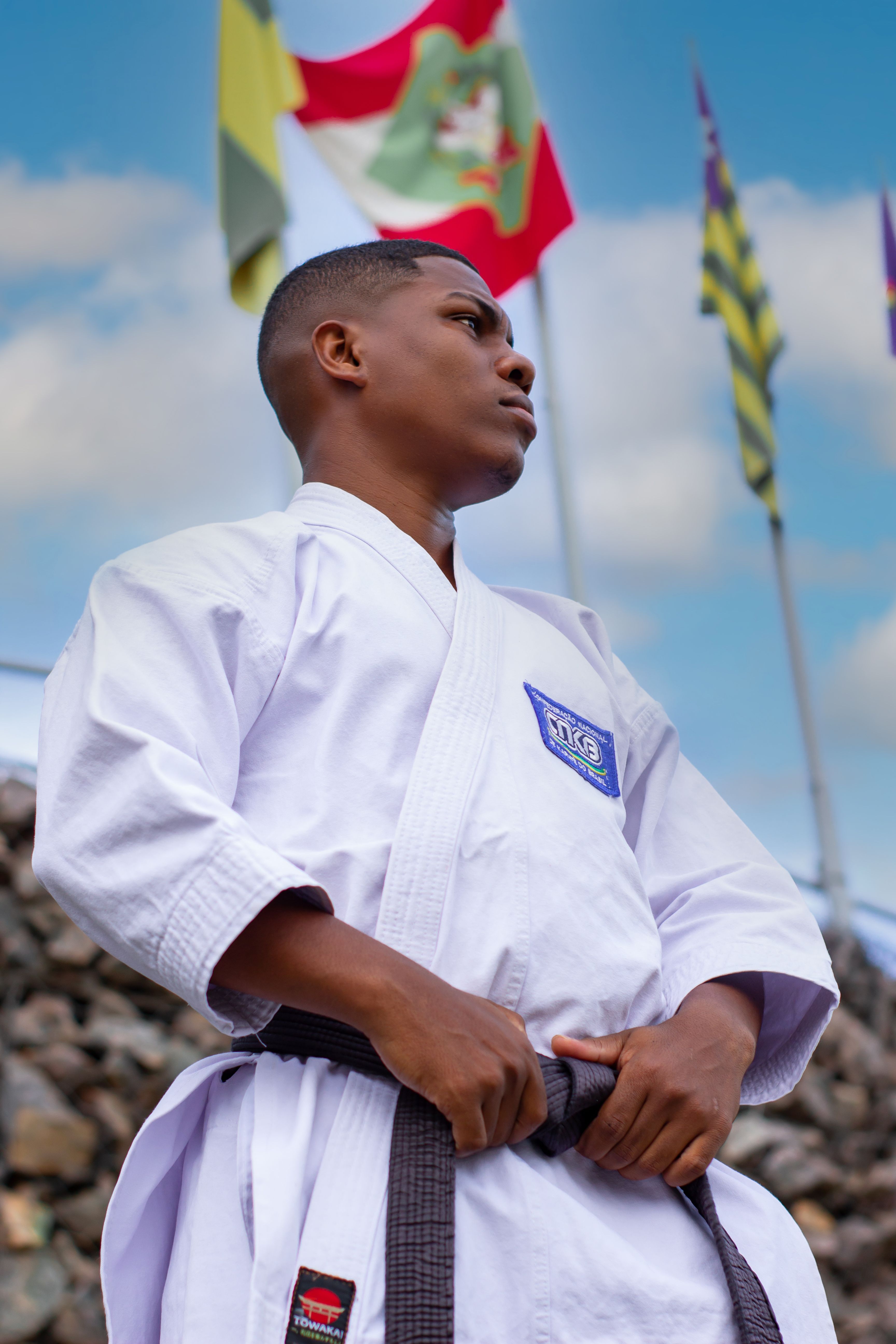 Confident athlete in judo uniform with black belt looks ready for competition outdoors.