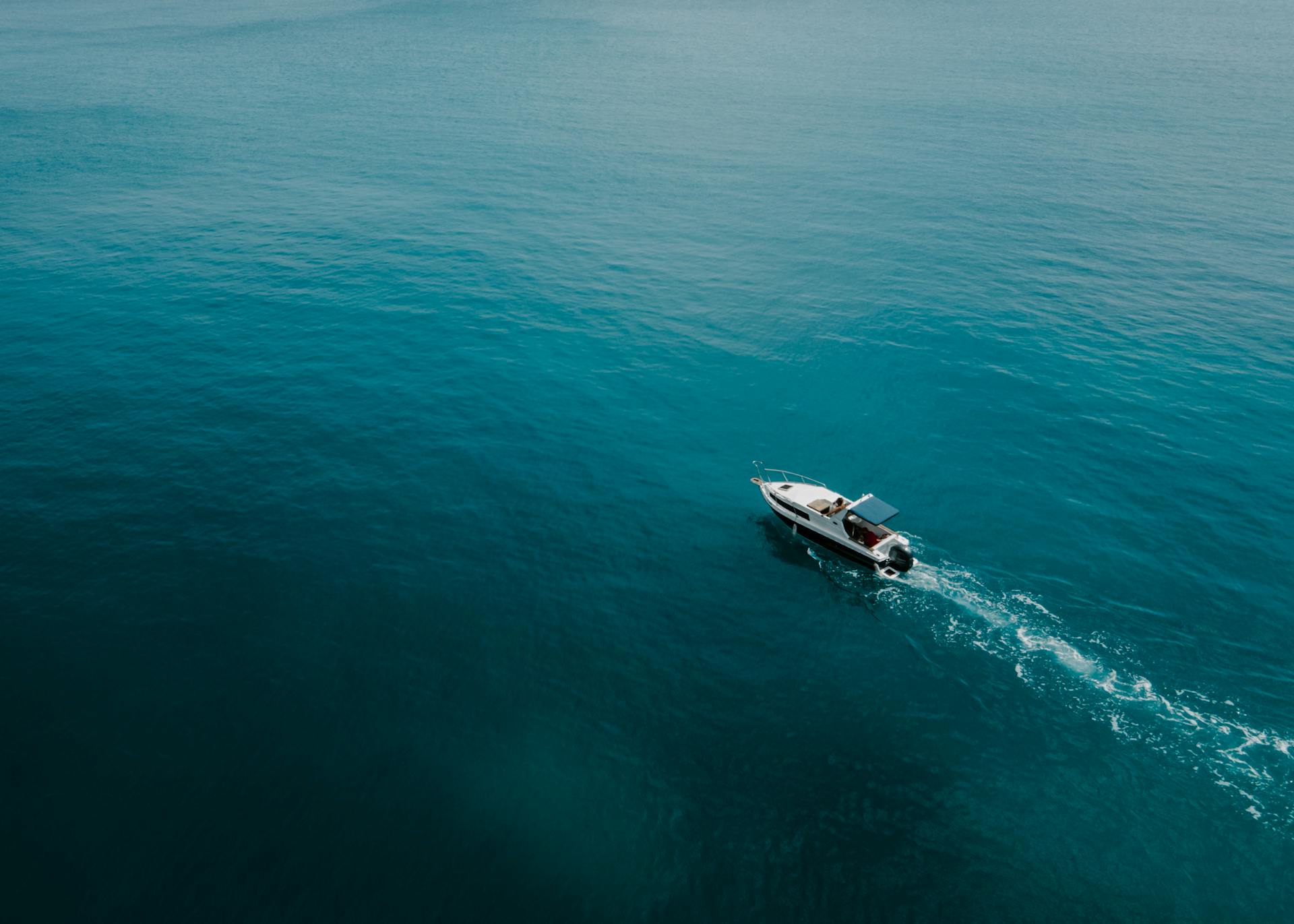 Aerial photo of a motorboat navigating through the vibrant turquoise sea, capturing a sense of adventure.