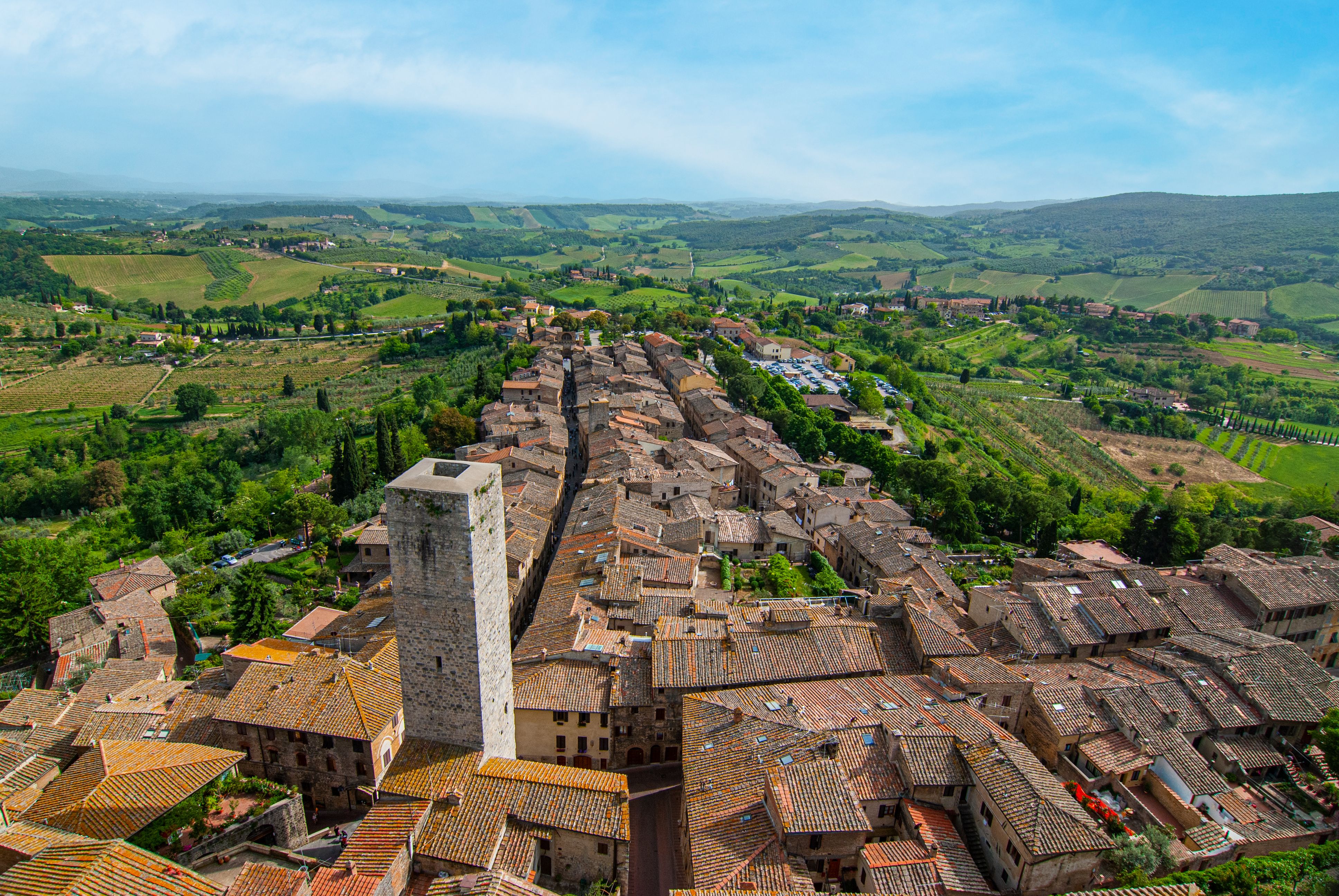 Aerial view of San Gimignano, Italy, showing medieval towers in Tuscany’s lush landscape.