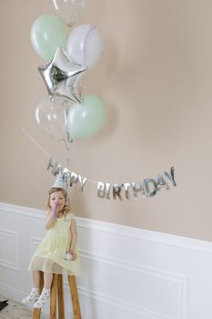 A child enjoying a birthday party with balloons and decorations indoors.