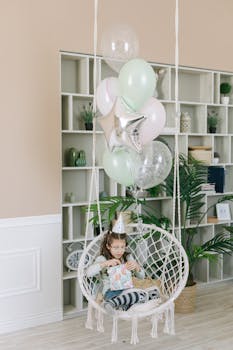 Girl enjoying a birthday party with balloons and presents in a cozy indoor setting.